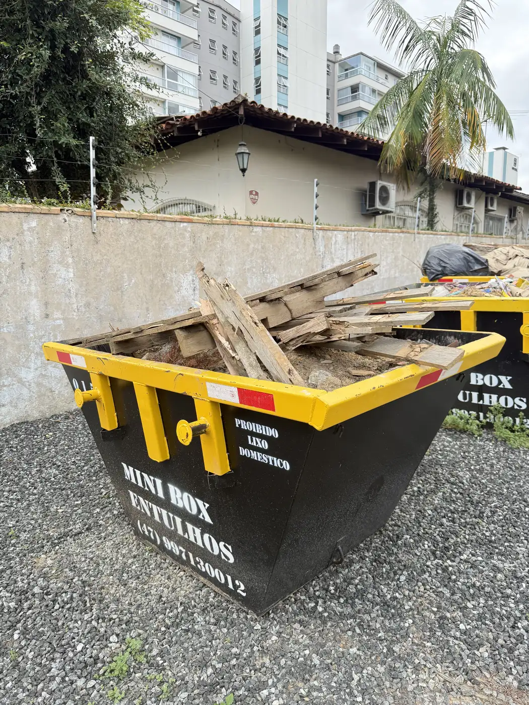Mini Box, a caçamba de entulho compacta da Mini Box Entulhos, cheia de restos de obra em uma rua de Blumenau